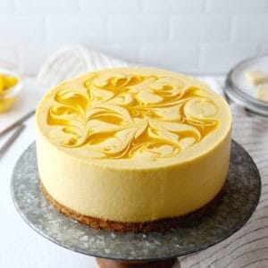 no-bake mango cheesecake on a cake stand