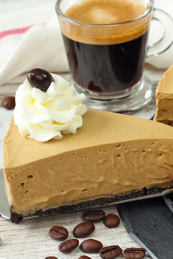 no bake coffee cheesecake portion on a table with a shot of expresso and some coffee granules