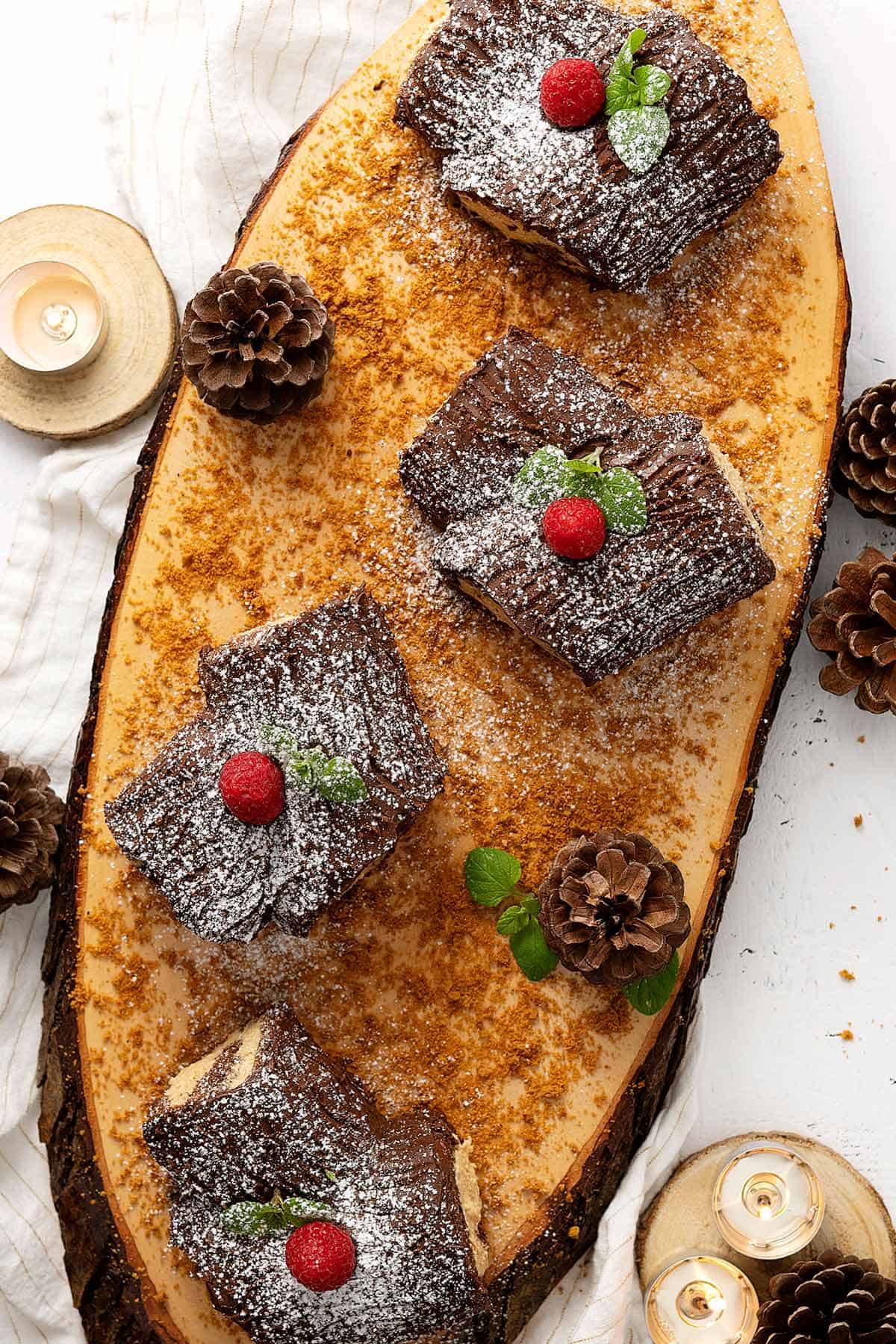 Overhead of four mini yule log cakes on a wooden tray.