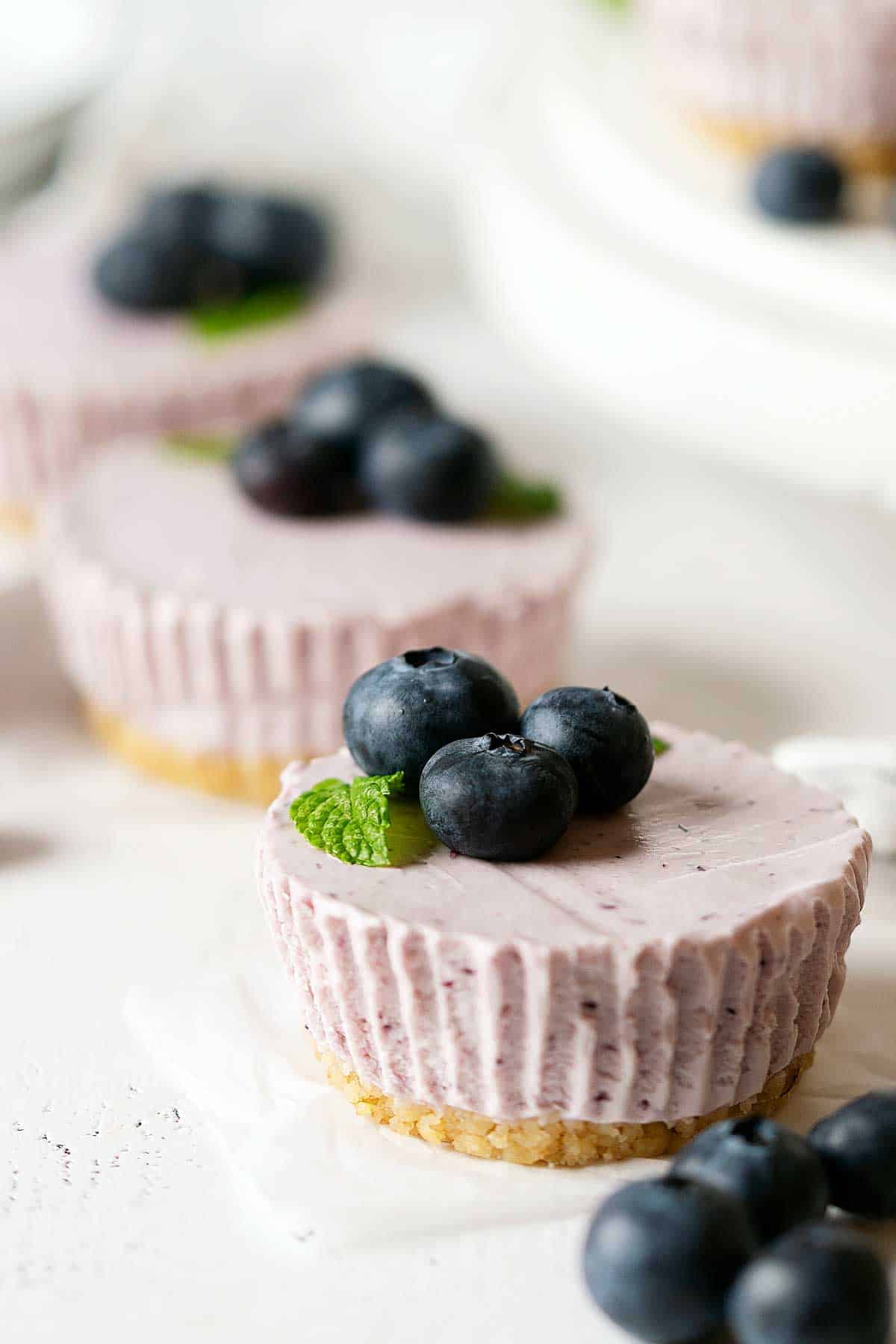 3 mini blueberry cheesecakes on a table.