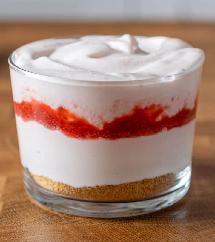 vaso con una crema rosa clara y mermelada de fresa.